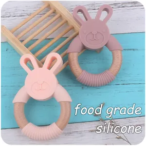 Detail of pink silicone rabbit teethers with natural beech wood rings on a blue wooden base