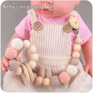 Detailed shot of wooden baby pacifier clip with crochet beads and teething rattle toy