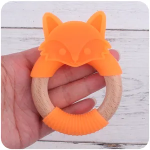 Gros plan d'un anneau de dentition avec bois naturel et tête de renard en silicone orange