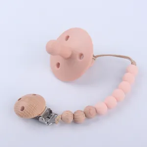 Close-up of pink food-grade silicone pacifier with natural wood and silicone bead clip chain