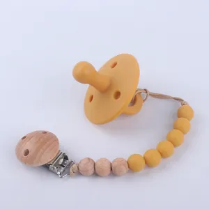 Mustard yellow silicone baby pacifier with a matching beaded wooden clip chain