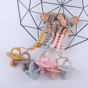 Five sets of silicone baby pacifiers and matching wooden beaded clips in various colors