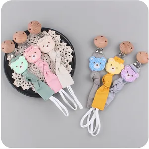 Dettaglio di catenelle per ciuccio colorate con clip in faggio e testine di orsetto in peluche