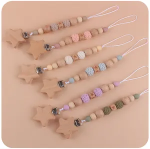 Detail view of handmade wooden pacifier clips with star beads and colorful crochet balls