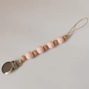 Detail of baby pacifier clip with pink silicone beads and natural wooden beads on white