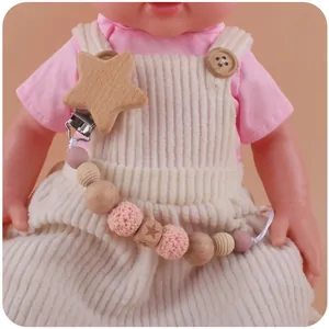 Close-up of a wooden star pacifier clip with colorful beads on a doll's outfit