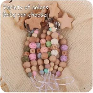 Detail of wooden star pacifier clips with colorful silicone and crochet beads on fabric