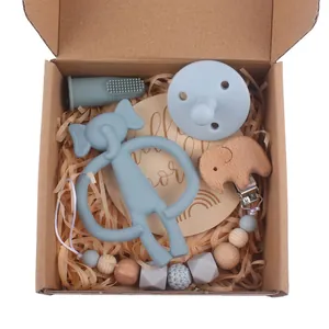 Baby care gift set featuring grey elephant silicone teether, pacifier, and wooden clip chain