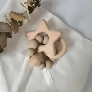 Baby star beech wood teething ring with silicone beads on a soft white cloth background