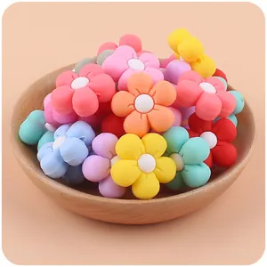 Macro detail of colorful silicone flower beads for DIY pacifier clips in a wooden tray