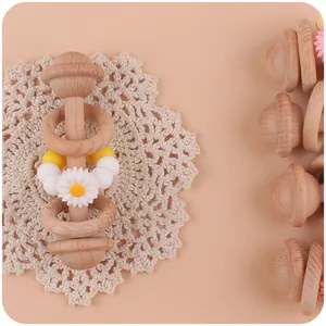 Close-up of wooden baby rattle with silicone daisy beads on white lace background