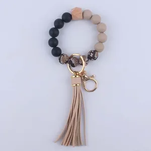 Macro detail of silicone beads, wooden geometric bead, and snakeskin tassel keychain charm