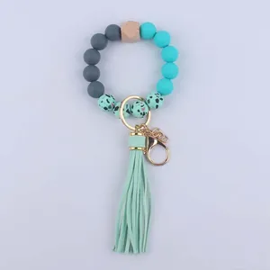 Detail of beaded wristlet keychain with silicone beads, wood accent, and green tassel