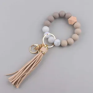 Detail van siliconen kralenarmband met geometrische houten kraal en lange lederen kwast