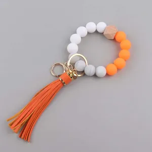 Detail van siliconen kralenarmband met feloranje kwastje en gouden metalen ring sluiting