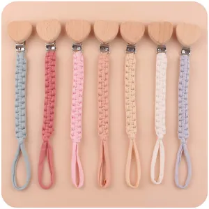 Detail view of seven colorful braided cotton pacifier clips with heart shaped beech wood