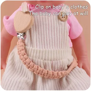 Detail of pink hand-woven pacifier chain with beech wood heart clip on baby clothes