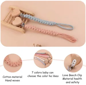 Detail of handmade cotton braided baby pacifier clip with heart-shaped beech wood fastener