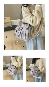 Detail view of a multi-pocket grey canvas shoulder bag showing straps and drawstring closure
