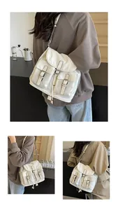 Detail of white canvas bag showing multi-pocket layout and black buckle strap accents