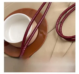 Dettaglio della borsa a tracolla bordeaux scamosciata con spalline tonde e texture
