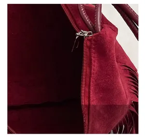 Dettaglio borsa a tracolla in pelle scamosciata bordeaux con zip e nappe laterali
