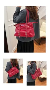 Detailed view of large red glossy tote bag with decorative buckle straps and dual handles