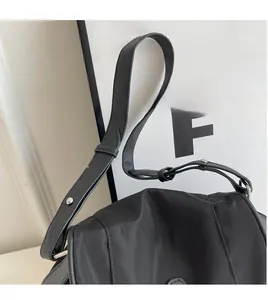 Detail of adjustable long shoulder strap with silver buckle on black canvas bag