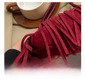 Dettaglio macro della borsa in pelle scamosciata bordeaux con cuciture e frange