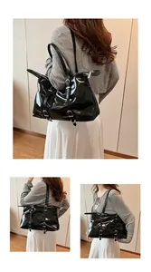 Detail view of large black glossy tote bag with buckle straps and silver zippers