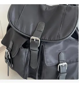 Detail of silver buckles and premium nylon texture on a large black multi-pocket bag