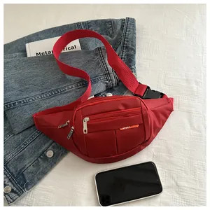 Detail of red canvas waist bag with zipper pockets and sport label on denim background