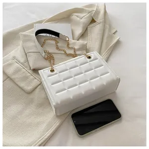 Vista plana de un bolso acolchado blanco con cadena dorada y detalles de blazer