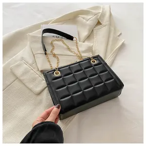 Detalle de bolso acolchado negro con cadena sobre blazer beige y herrajes dorados