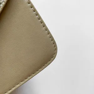 Detailed close-up of premium leather texture and precise stitching on a beige shoulder bag