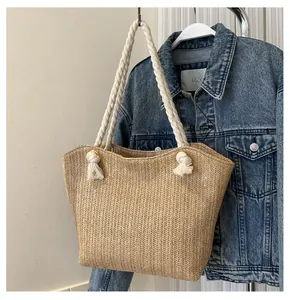 Detail of hand-woven straw tote with thick white cotton rope handles and knot details