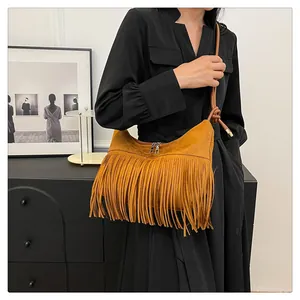 Dettaglio della borsa in pelle scamosciata con lunghe frange e tracolla con nodo
