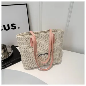 Détail du sac cabas beige tressé avec poignées en cuir rose et broderie Summer