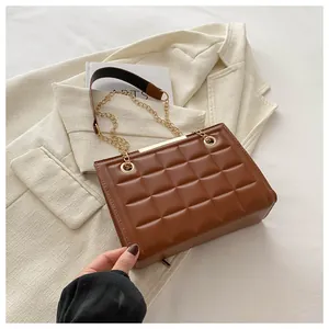 Detalle del bolso acolchado marrón con cadena dorada y ribete metálico elegante