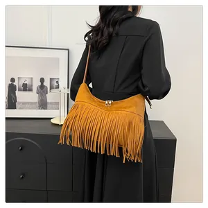 Dettaglio della borsa hobo in pelle scamosciata marrone con frange indossata dalla modella