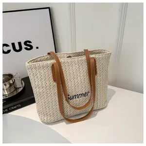 Détail du sac cabas en paille tressée avec anses en cuir marron et broderie Summer