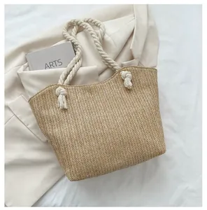 Detail of handwoven straw tote with thick cotton rope handles and decorative tassels