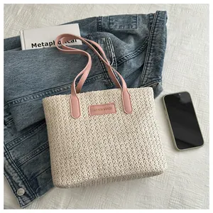 Detailed straw tote bag with pink leather straps and a stylish fashion patch on the front
