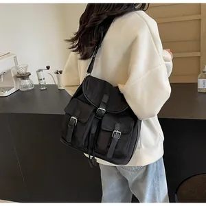 Detail of black canvas crossbody bag featuring functional utility pockets and silver buckles