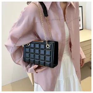 Detalle del bolso de hombro negro acolchado con cadena dorada en el modelo