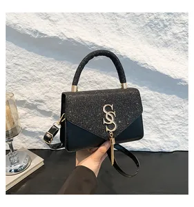 Détail du sac à main en paillettes noires avec lettre S dorée et pompon métallique