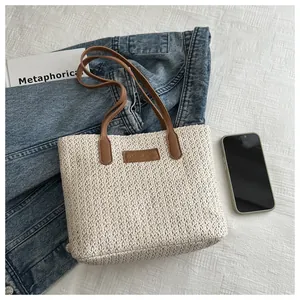 Detailed close-up of woven straw tote bag texture and fashion leather patch detail