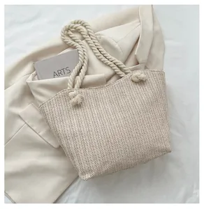 Detail of woven straw tote bag with thick cotton rope handles and golden metal eyelets