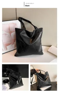 Detail view of black geometric faux leather tote bag showing textured stitching and strap