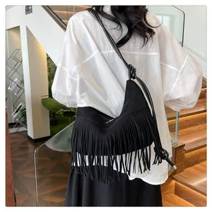 Dettaglio di una borsa hobo in camoscio nero con lunghe frange e tracolla con nodo